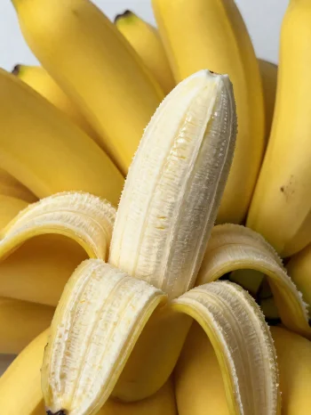 Fresh bananas whole and sliced, in a bowl and on a rustic table
